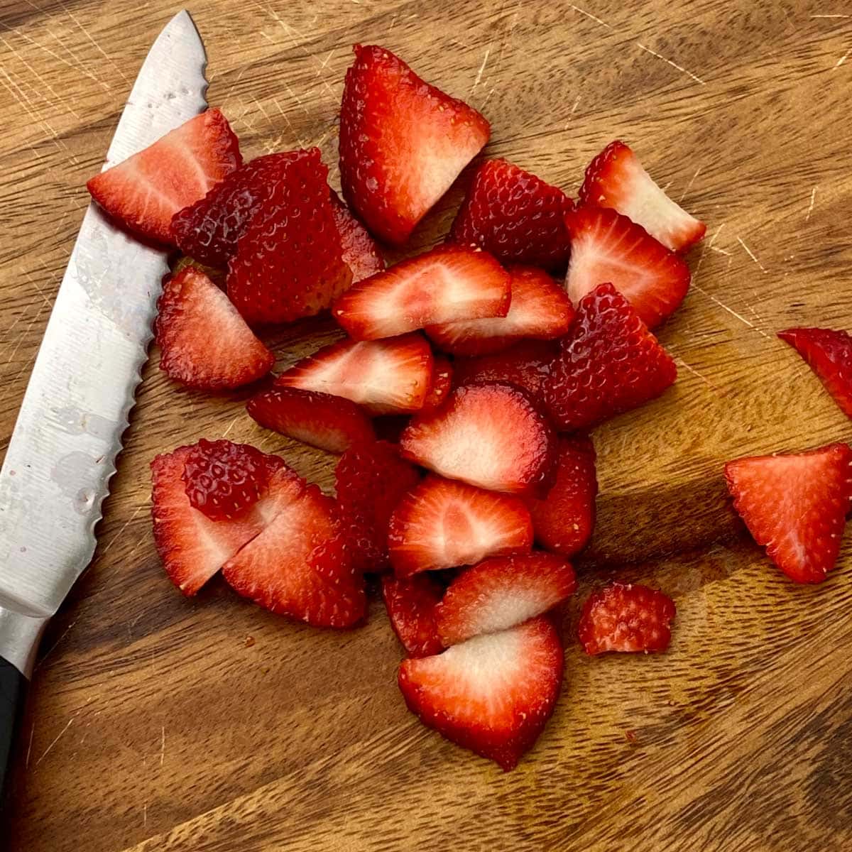 sliced strawberries sitting on a cutting board next to a knife