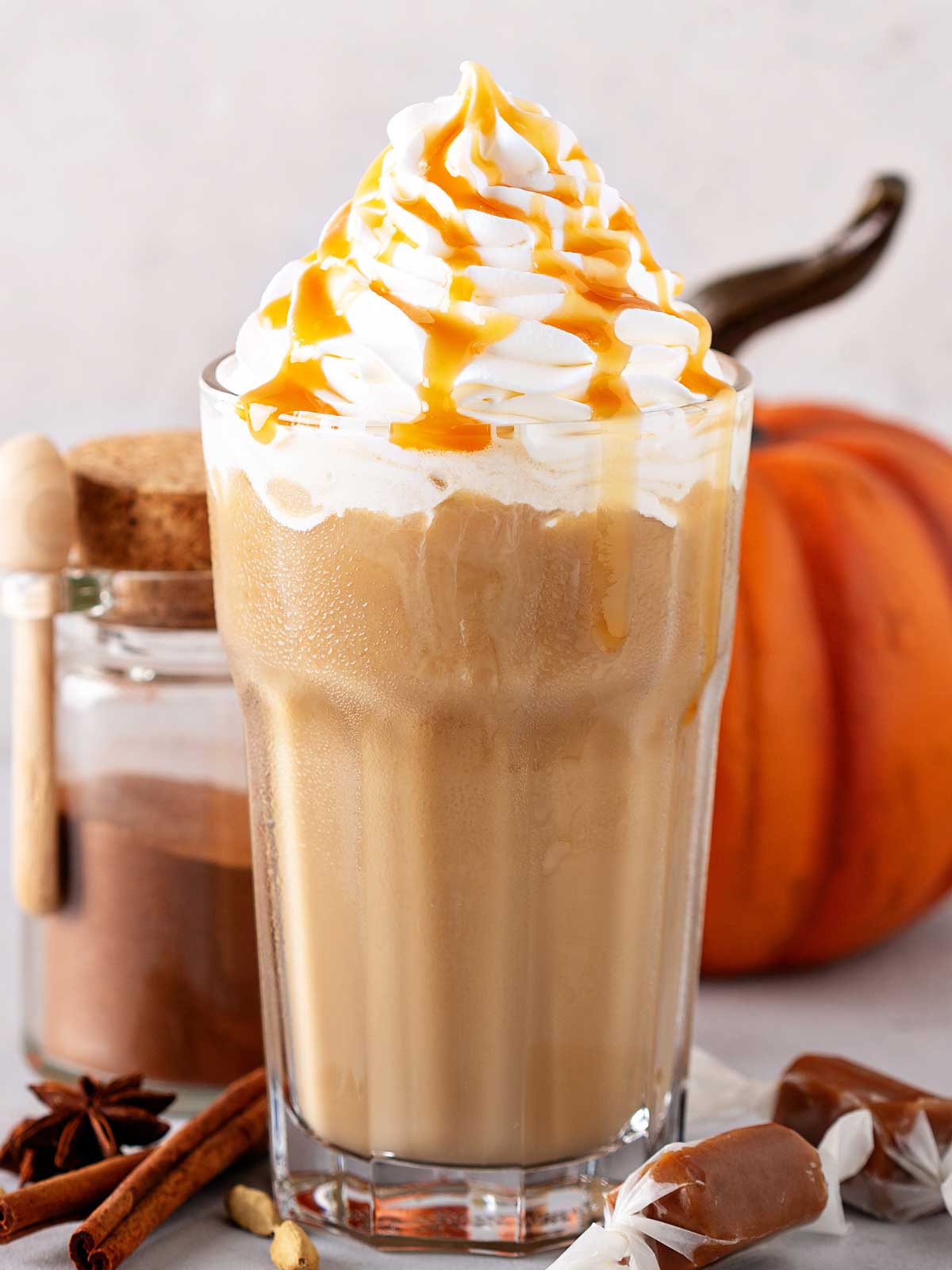 healthy pumpkin smoothie in tall glass with a pumpkin in the background.