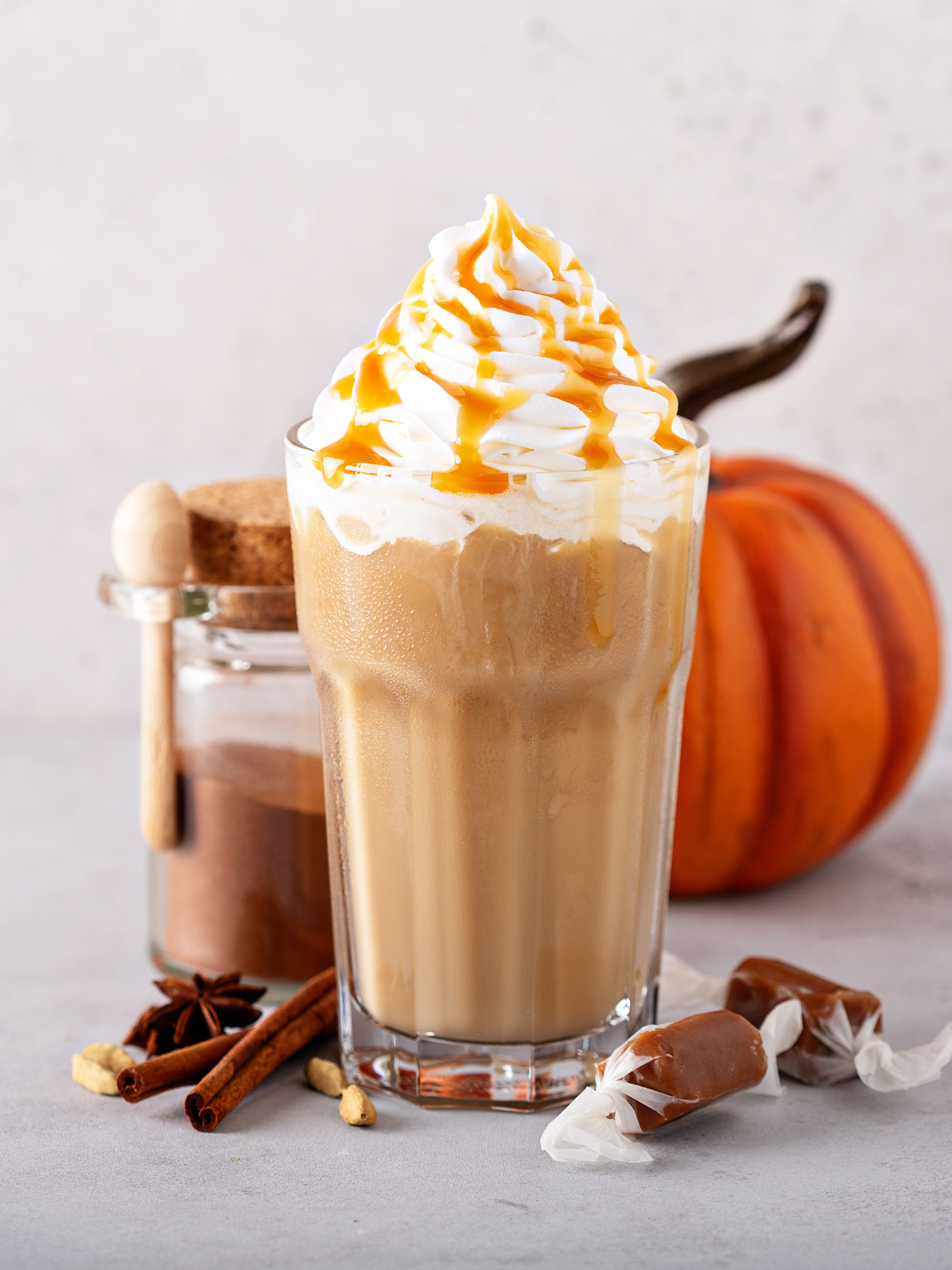 healthy pumpkin smoothie in tall glass with a pumpkin in the background.