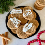 Gluten free ginger cookies drizzled with white icing on a black plate