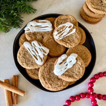 Gluten free ginger cookies drizzled with white icing on a black plate