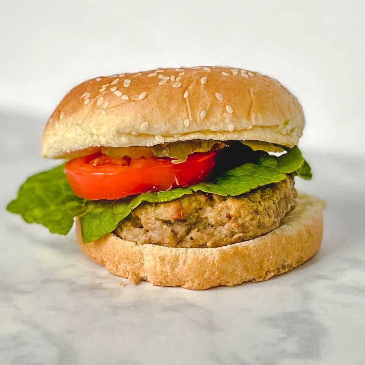 side view of a turkey burger on a bun with lettuce and tomato.