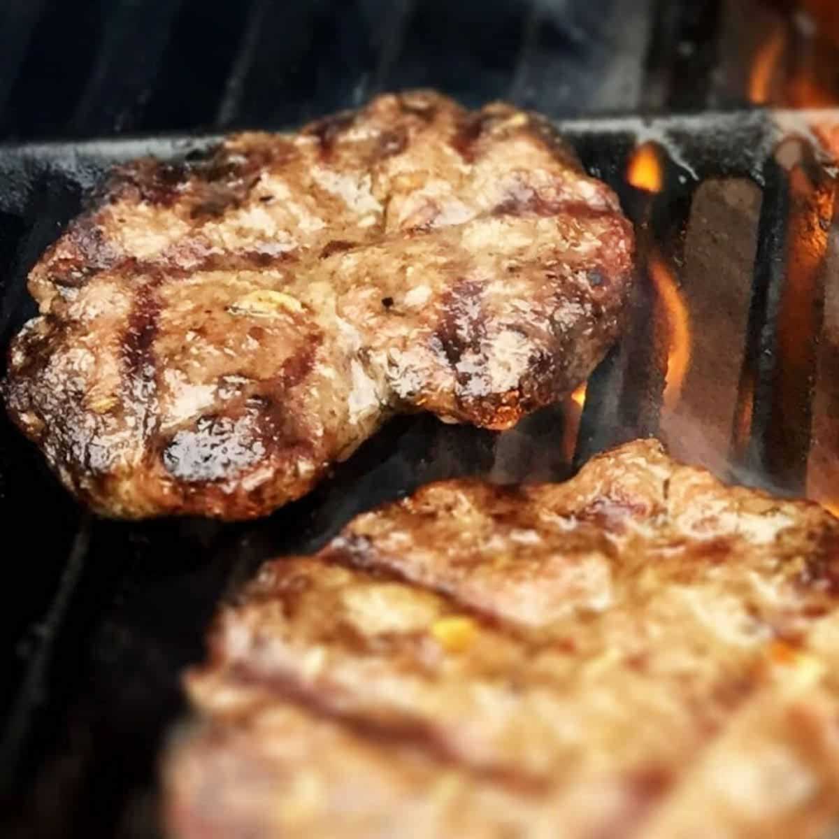 burgers on a grill with a flame