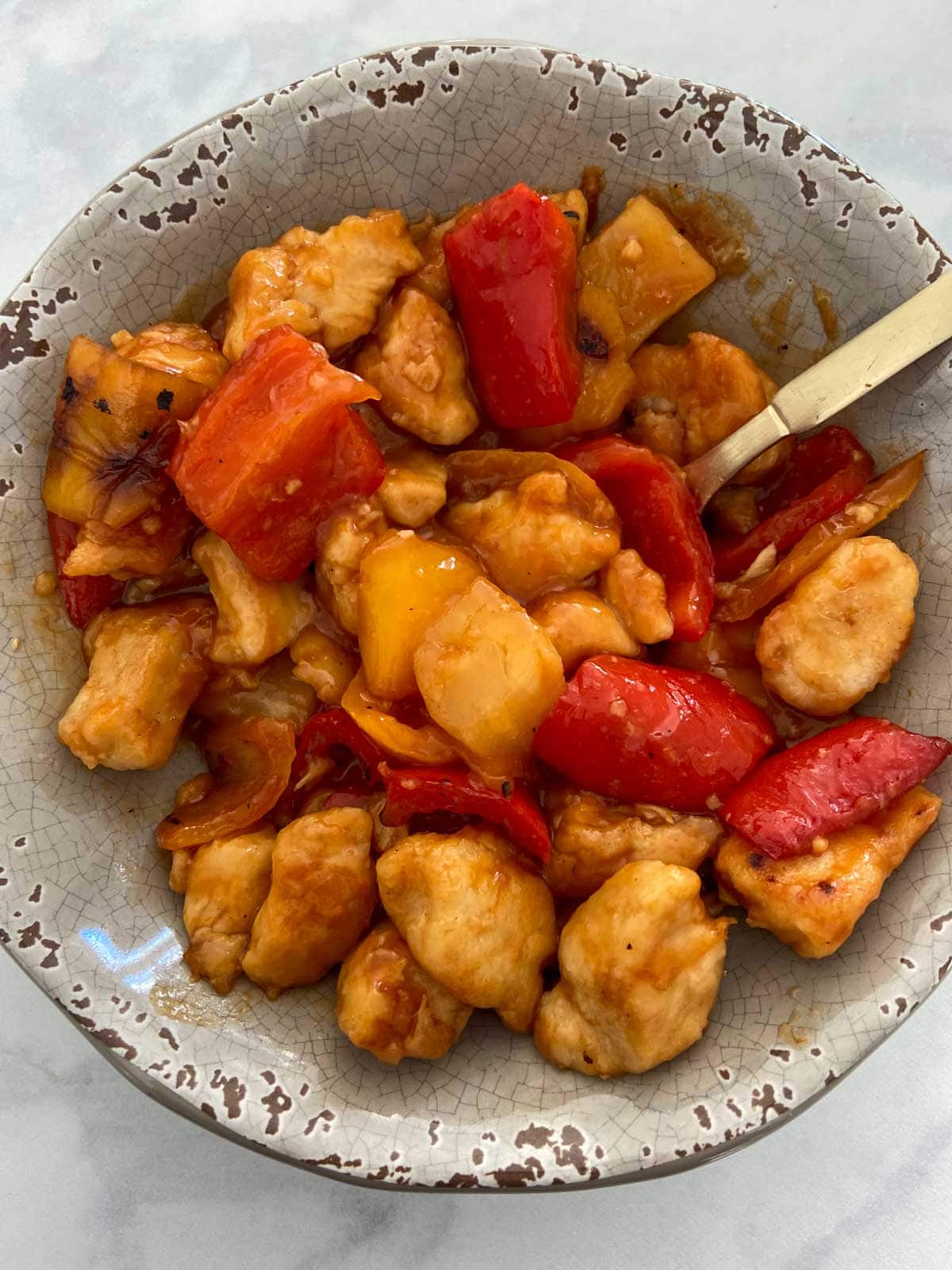 gluten free sweet and sour chicken in a bowl with a spoon.