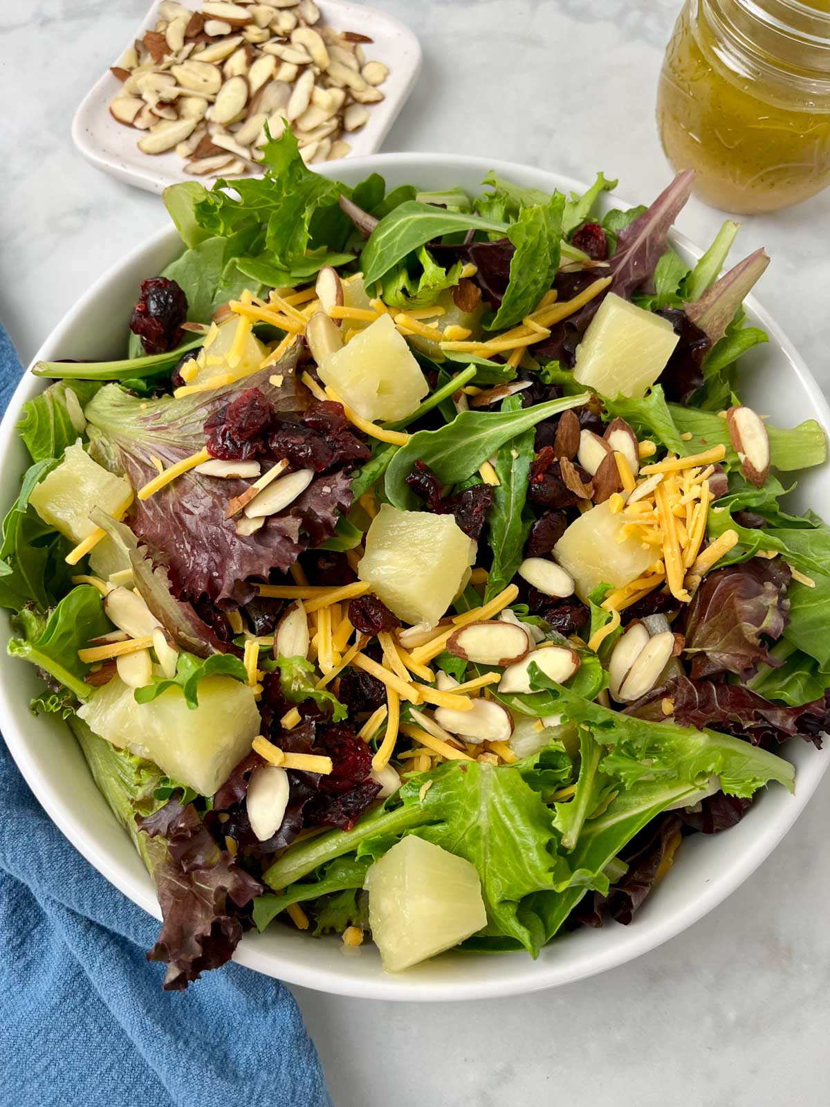 close up of a hawaiian sald with almonds and dressing in the background.