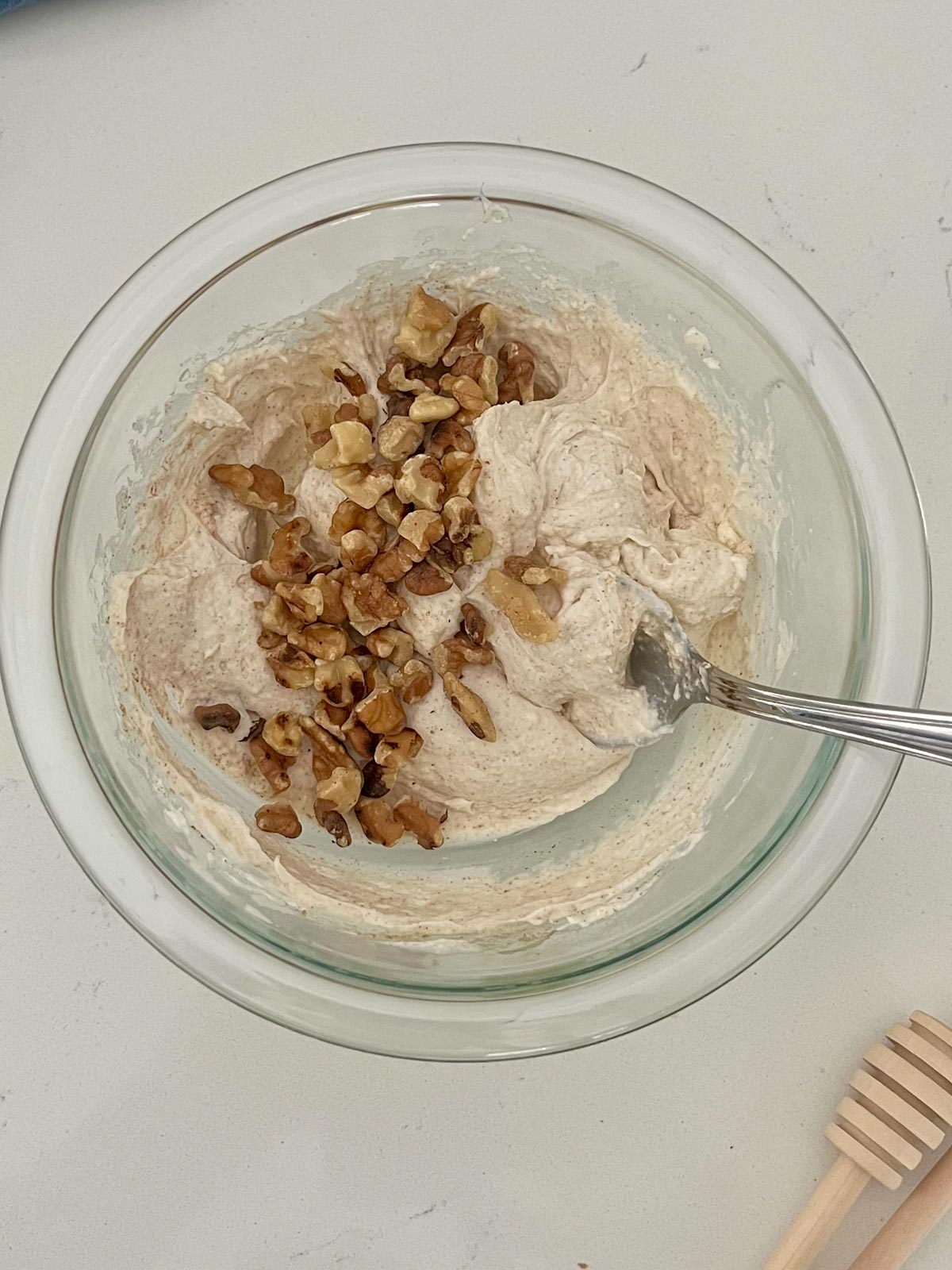 honey walnut cream cheese ingredients mixed together in a bowl with walnuts on top