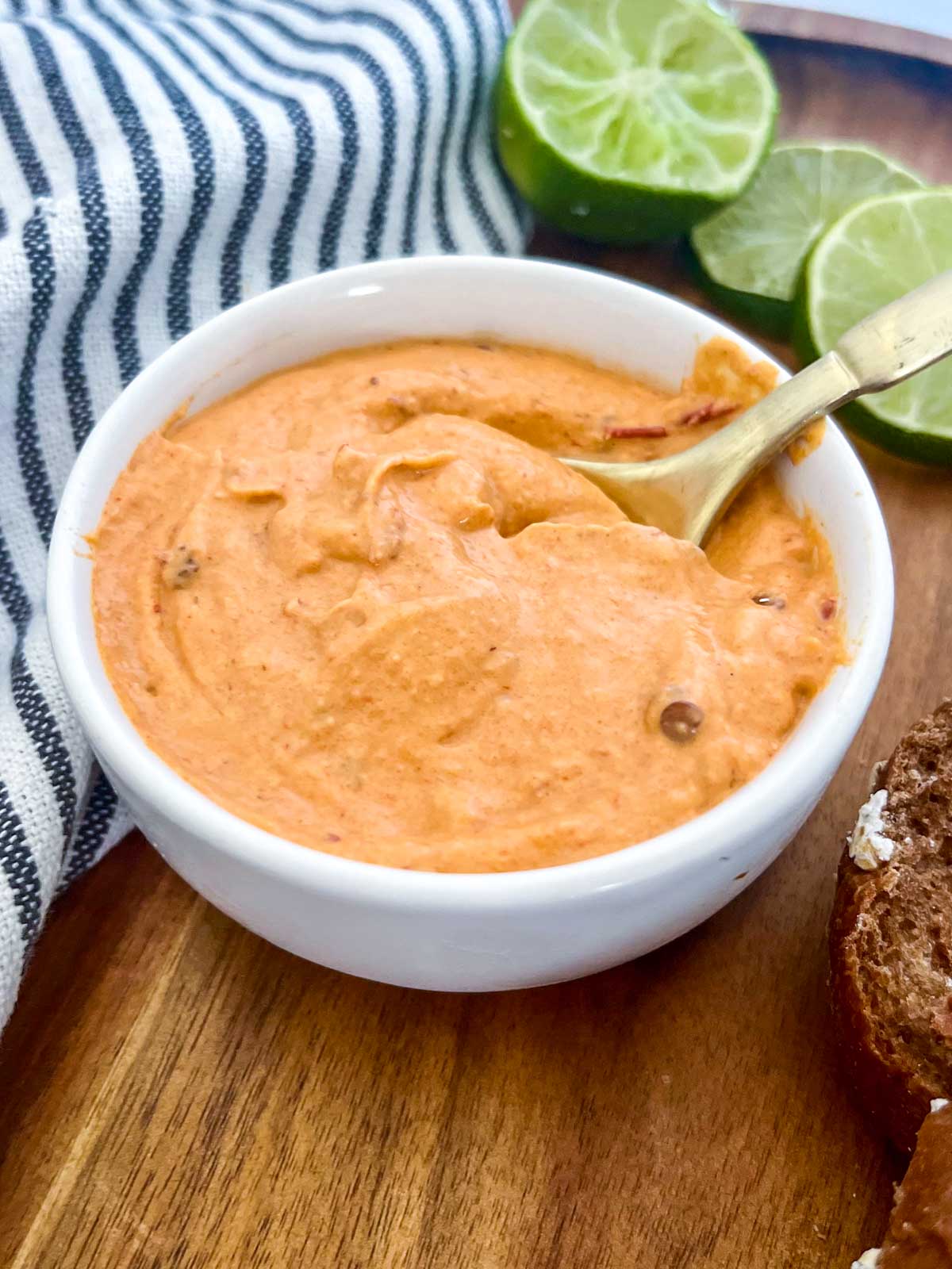 chipotle southwest sauce with limes, brown bread and a blue towel in the background. 