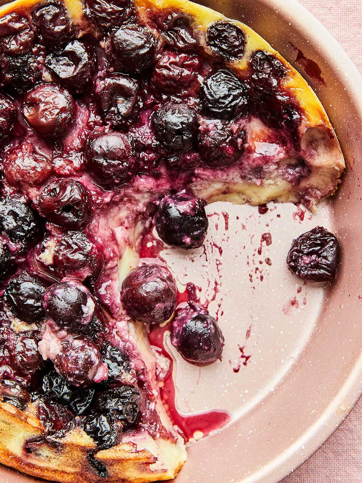 Cherry clafoutis in a pan with a piece missing. 