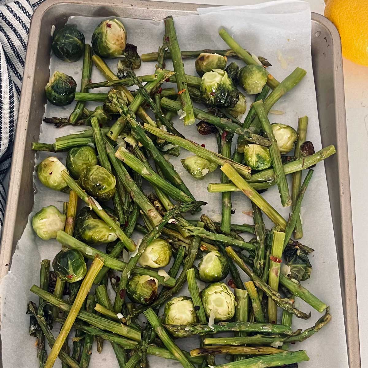 roasted Brussels sprouts and asparagus on a sheet pan topped with asparagus.