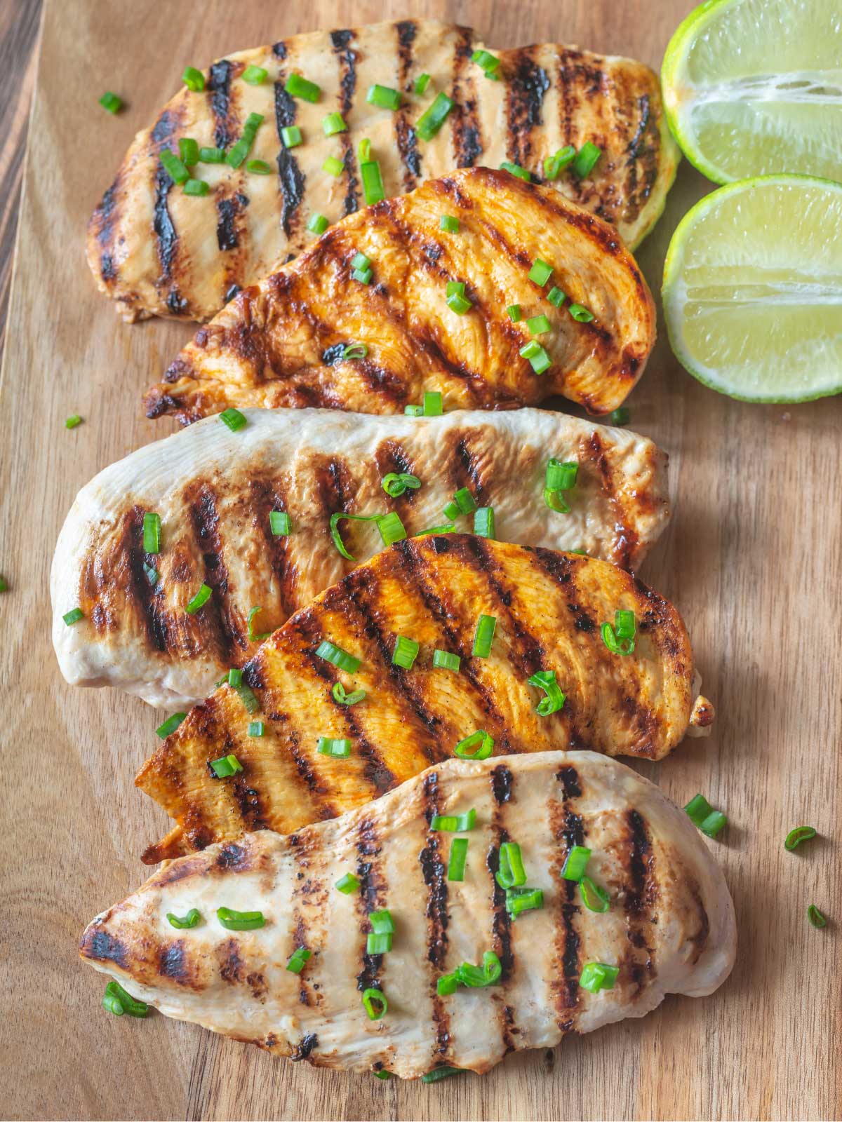 grilled chicken breasts on a wood cutting board